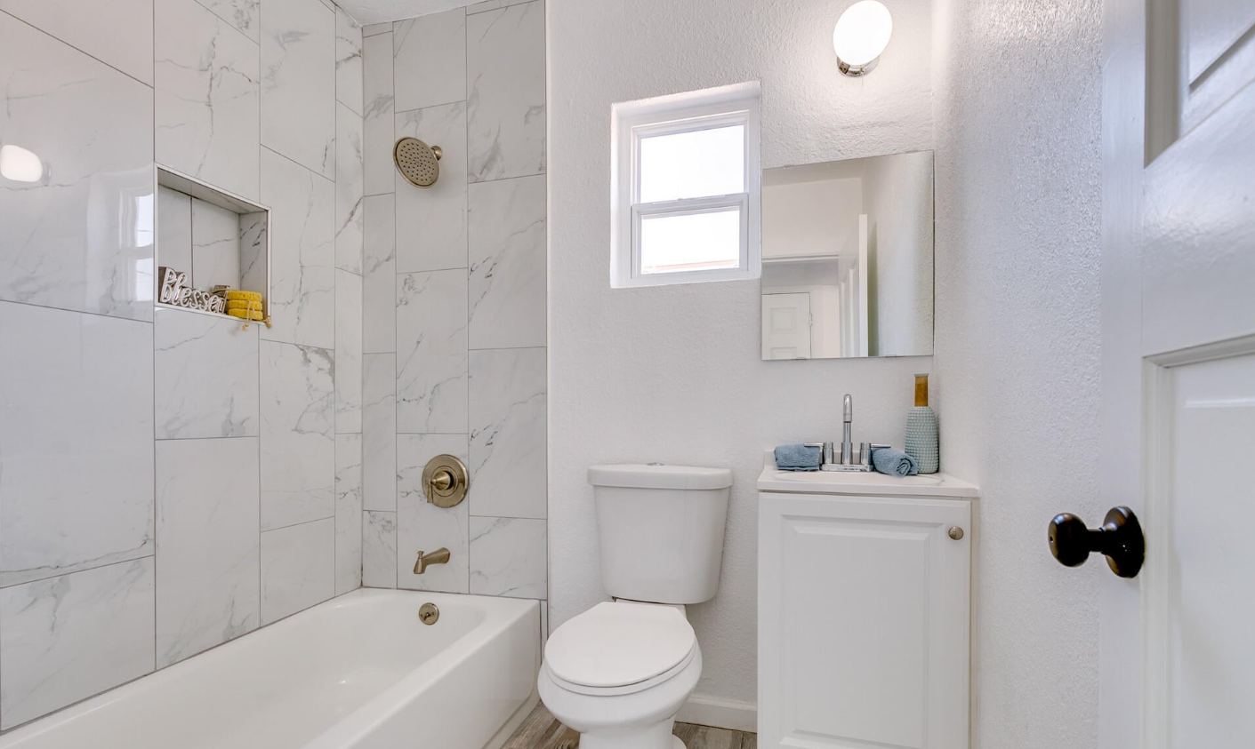 Remodeled white bathroom with new tub and toilet