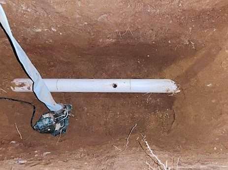 Damaged PVC supply line exposed in a trench